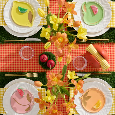Colorful table setting with floral centerpieces, colorful plates, and a checkered tablecloth.